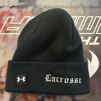 Black beanie with 'Lacrosse' and Under Armour logo on a blurred background