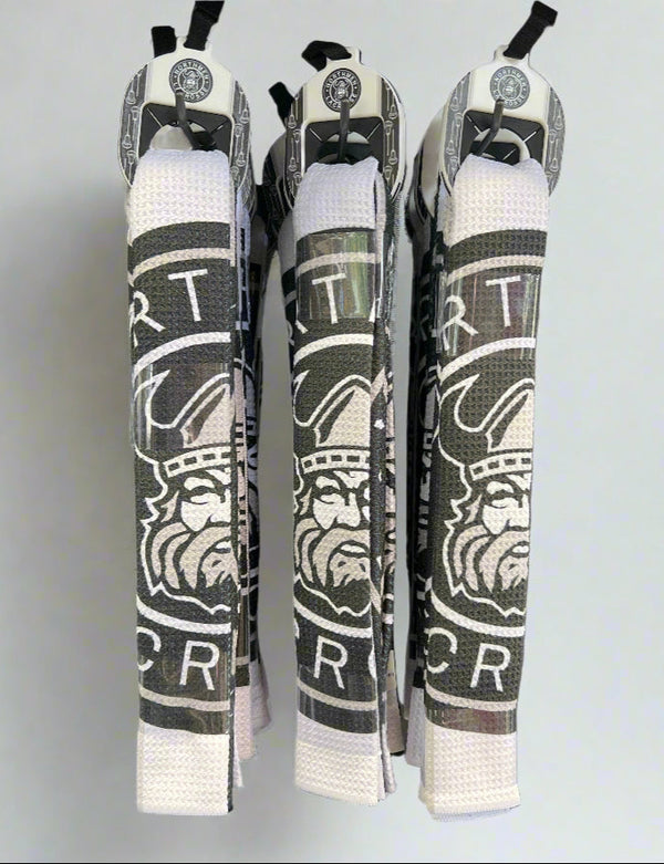 Three white and black towels with a stylized Viking head logo and bold letters hang vertically, each displaying a Sanderson Lacrosse Northmen Towel Tag for Lacrosse Golf, set against a plain light background.