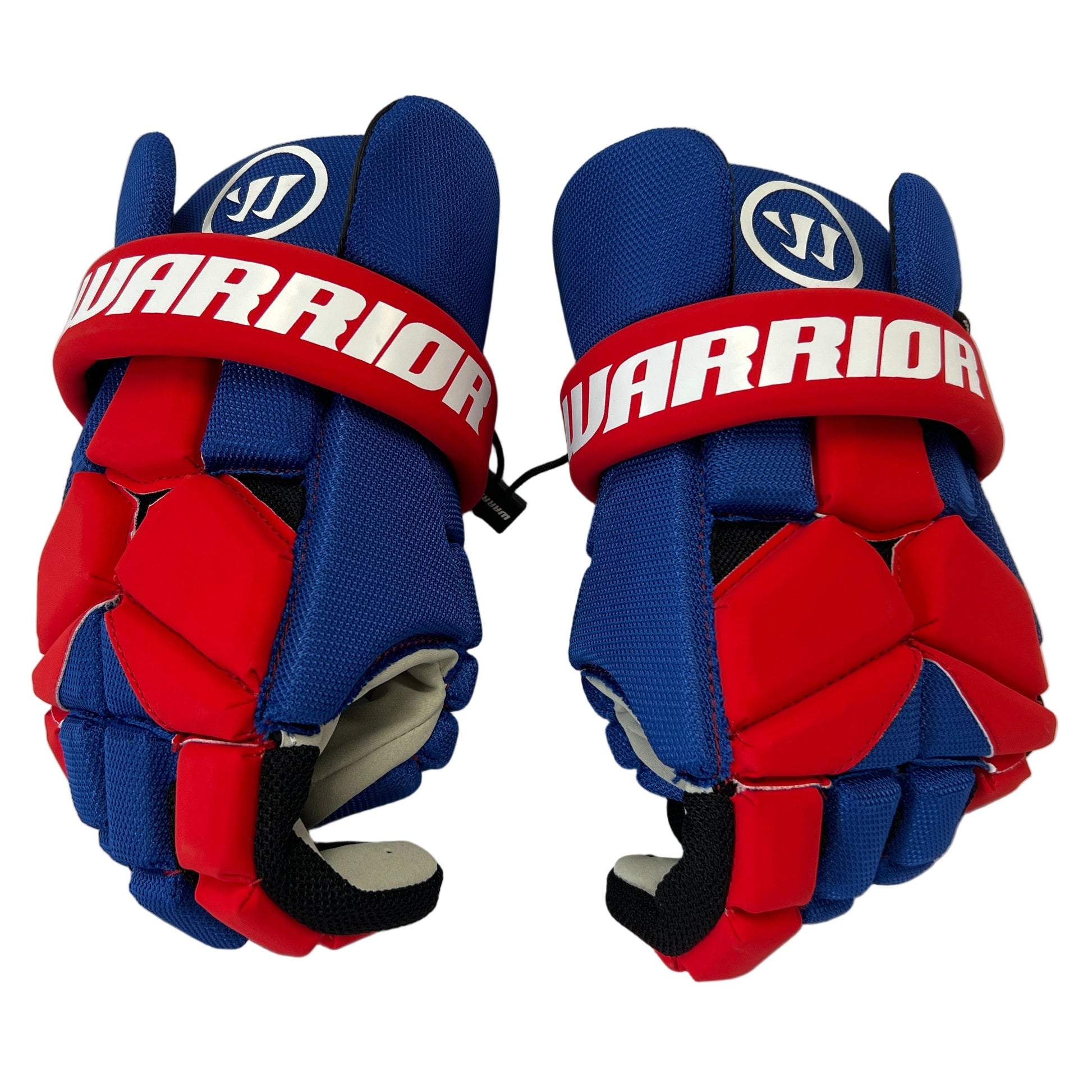 A pair of blue and red Sanderson Lacrosse Warrior Fatboy Lacrosse Gloves with white accents and "WARRIOR" in bold on the red strap, shown facing upward on a white background. These gloves offer top protective equipment for lacrosse.
