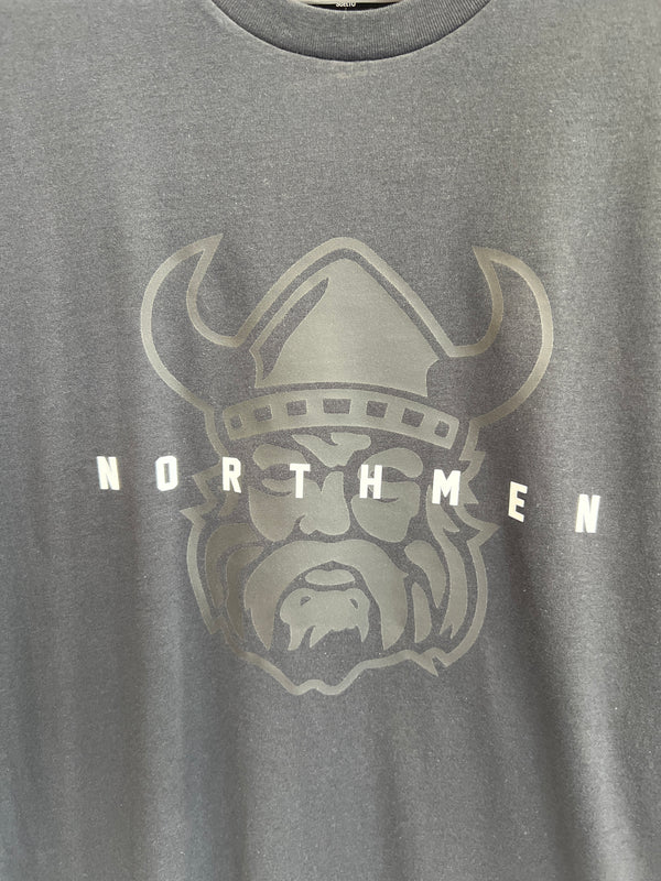 The Sanderson Lacrosse Northmen Lacrosse Under Armour Black on Black Cotton T-shirt features a stylized viking head helmet with bold "NORTHMEN" lettering across the design.