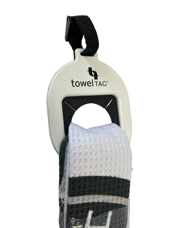 A close-up of the Northmen Towel Tag for Lacrosse Golf by Sanderson Lacrosse, holding a folded black and green striped towel with the towelTAG logo, attached to a black strap—ideal for lacrosse or golf gear.