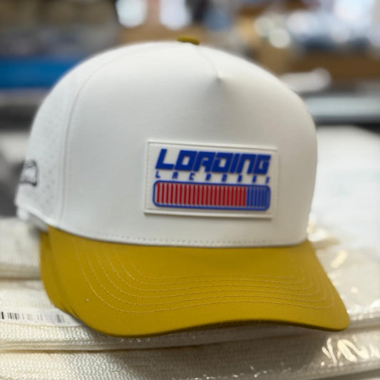 White and yellow loading lacrosse cap with a logo on a reflective surface